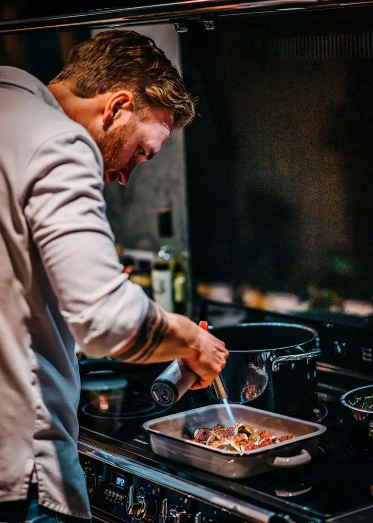 Privatkoch Sascha Zellinger verfeinert ein Gericht in der Küche – Live-Cooking-Event für exklusive Privatdinner